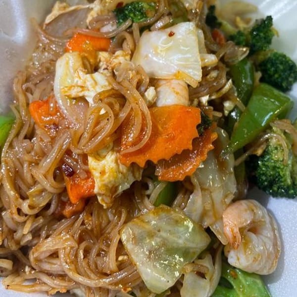 Close-up of stir-fried glass noodles with shrimp, broccoli, carrots, cabbage, and bell peppers.